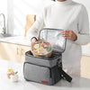 A woman holds an insulated thermal lunch bag containing food on a kitchen counter.