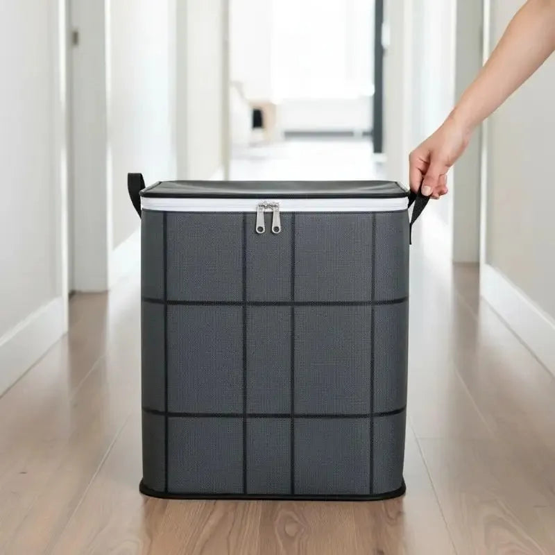 A hand is lifting a gray fabric storage organizer bag with a black handle in a bright hallway.