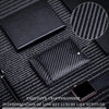 A black RFID protection wallet featuring a carbon fiber texture, displayed on a dark fabric background.