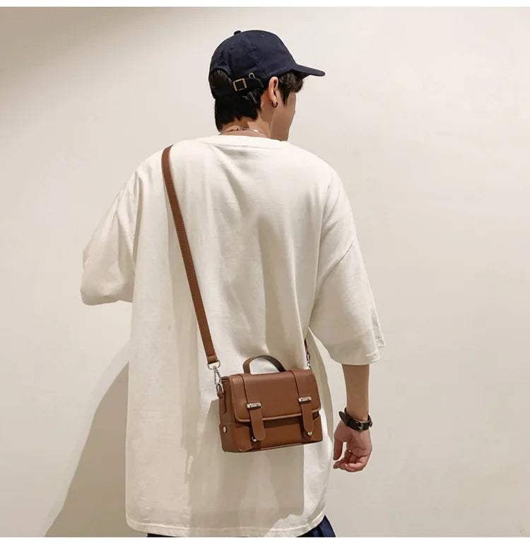 A man wearing a white t-shirt and a dark baseball cap is shown from the back, carrying a brown leather crossbody bag.