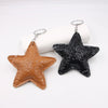 A leather star pendant key chain with a gold-colored finish and a black textured star pendant.