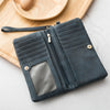 A dark gray leather wallet with a double zipper and card slots rests on a light wooden board.