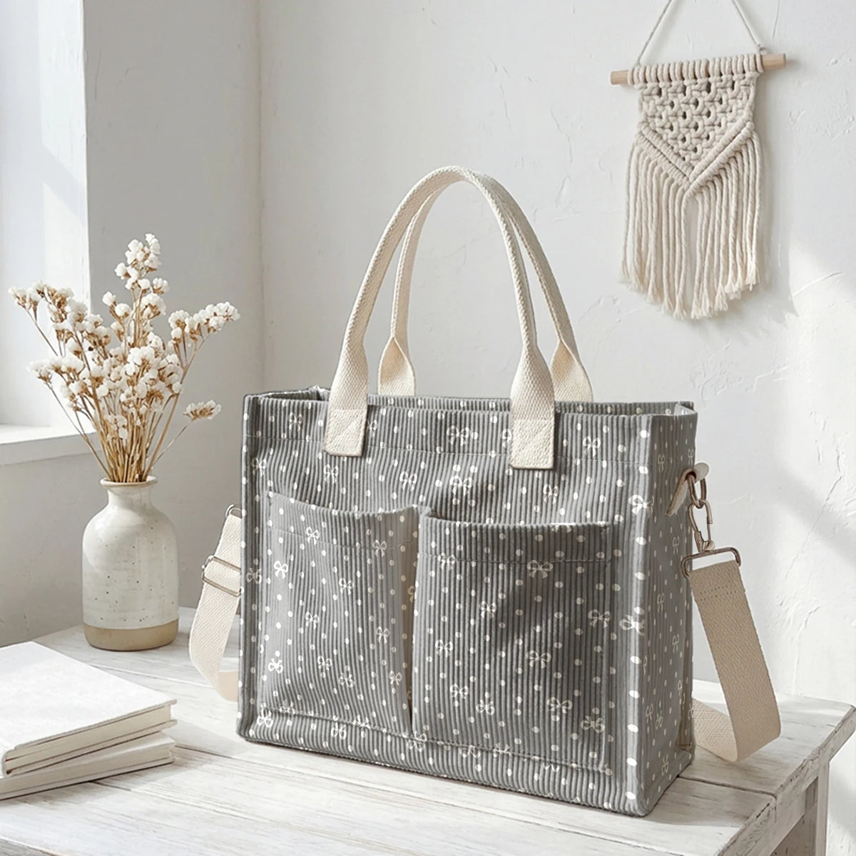 Un sac en toile à rayures de velours gris avec des pois clairs, exposé sur une surface en bois blanc.