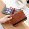 A brown leather passport holder with a black trim and an RFID blocking wallet is shown next to a passport.