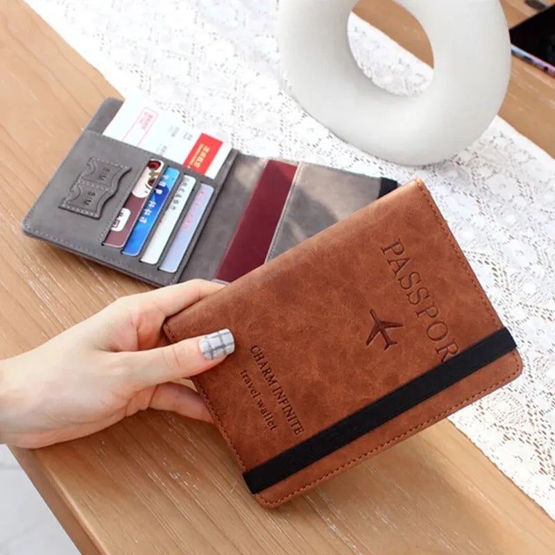 A brown leather passport wallet is shown next to a stack of cards and a white ring on a wooden surface.