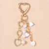 Gold-toned pearl bow heart keychain with a heart charm and a small heart charm.