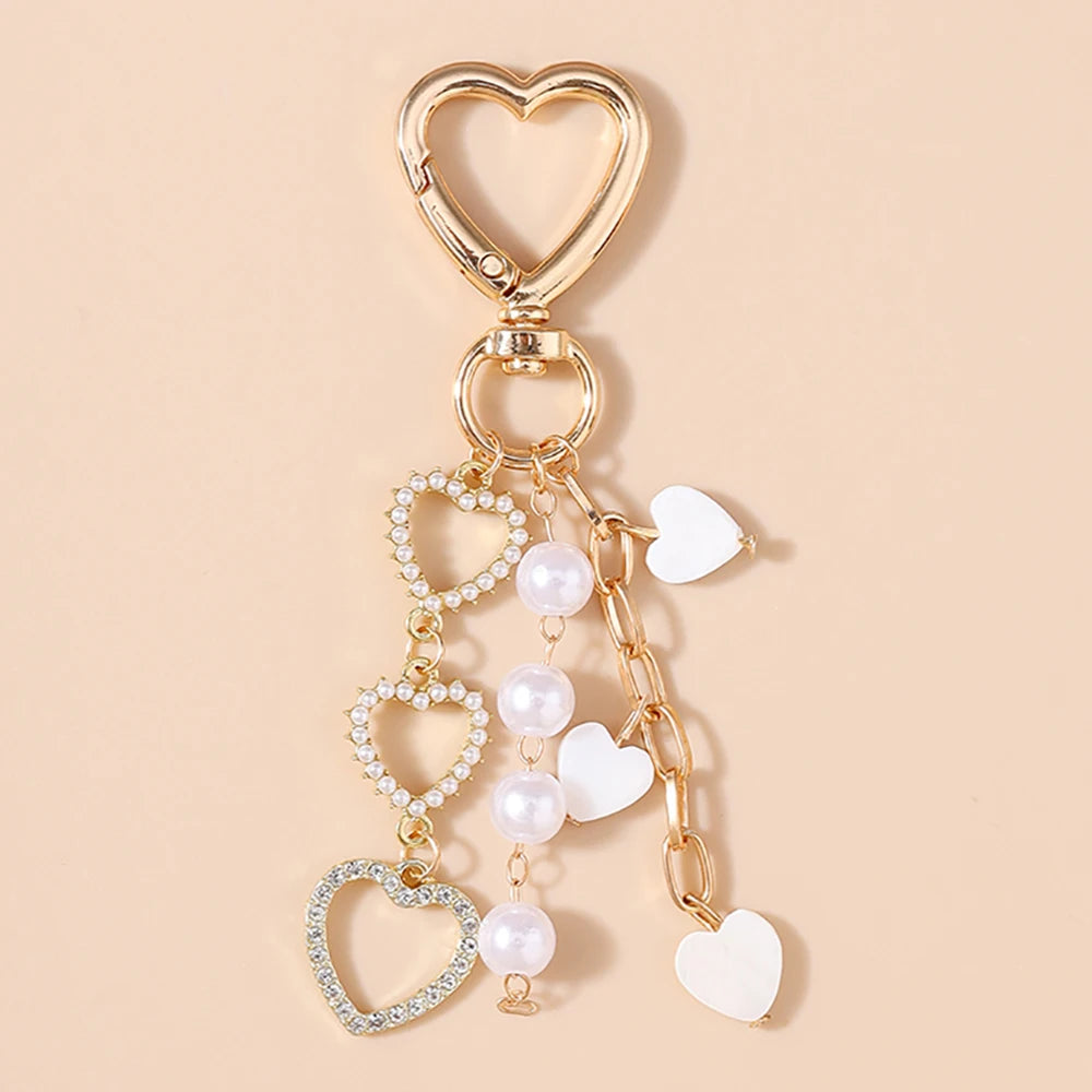 Gold-toned pearl bow heart keychain with a heart charm and a small heart charm.