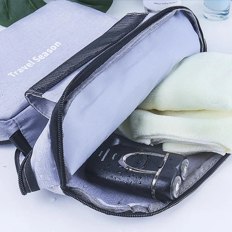Un sac de toilette étanche violet et gris suspendu est ouvert, montrant une peigne en métal noir à l'intérieur.