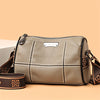 A beige luxury cowhide shoulder bag with stitching and a leather strap is displayed on a light background.