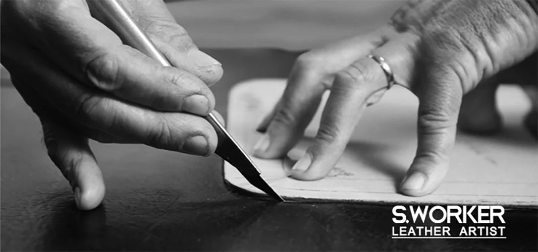 A close-up black and white photo shows a hand using a knife to cut leather for a leather artist.