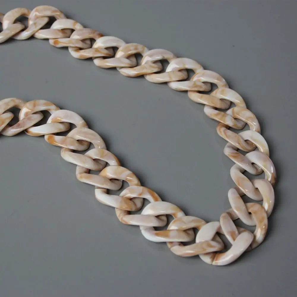 A flexible chain strap made of light beige and white marbled acrylic resin.