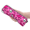 A hand holds a pink and black patterned leather pencil case featuring skulls, bats, and lips.