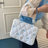 Bolso de computadora portátil acolchado blanco con detalles de lazo azul claro, sostenido por una persona.