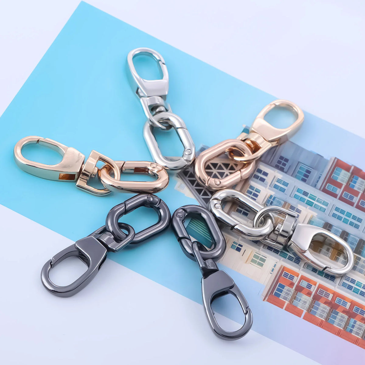 A collection of metal swivel lobster claw clasps and key rings displayed on a light blue background.