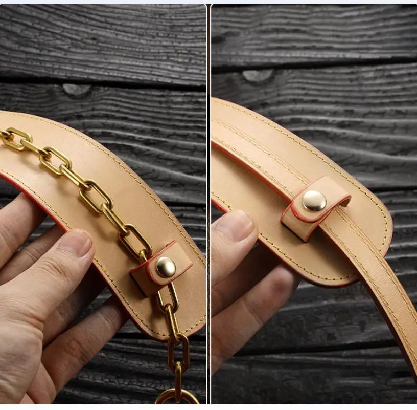 A close-up of a tan leather handbag carry loop with a gold chain and a brass clasp being held by a hand.