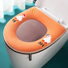 An orange plush waterproof toilet seat cover with small decorative figures on the lid.