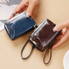 A hand holds a dark blue and brown vintage PU leather compact wallet with a coin pocket.