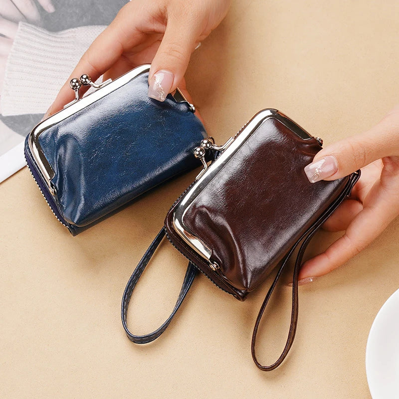A hand holds a dark blue and brown vintage PU leather compact wallet with a coin pocket.