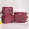 Two maroon insulated lunch tote bags with silver zippers and adjustable straps resting on a white surface.