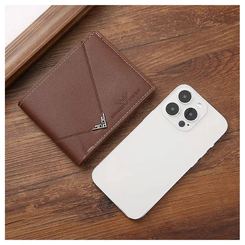 A brown leather bifold wallet is shown next to a white smartphone on a wooden surface.