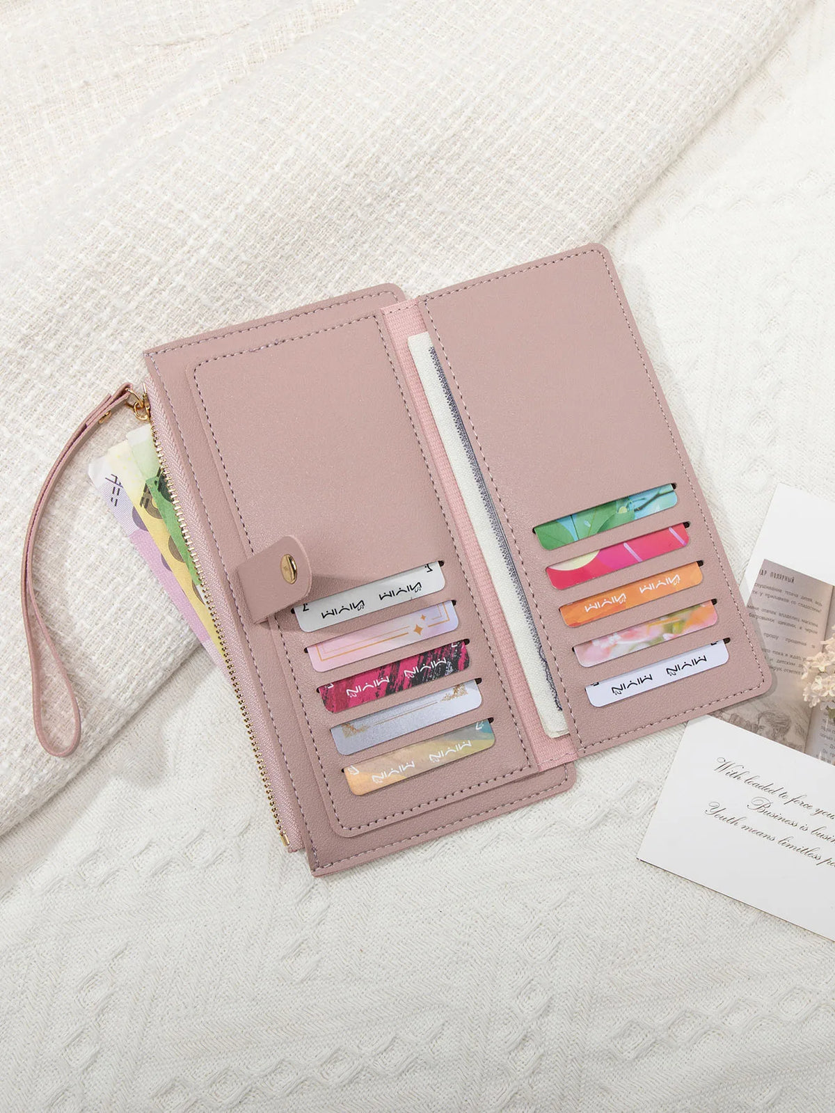 A pink PU leather coin purse and card holder with multiple slots for cards and coins, resting on a white textured fabric.