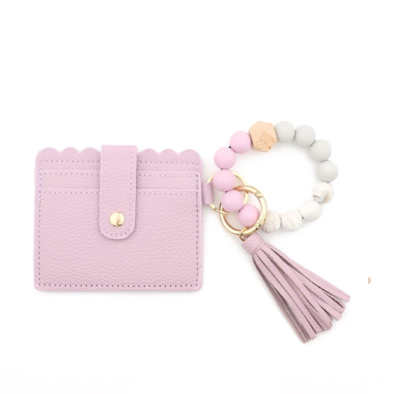 A pink silicone bead bracelet with a leather card holder and tassel charm.