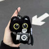 Colgante de gato negro de peluche como llavero, sostenido contra un fondo gris con una flecha apuntando al producto.