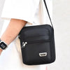 Sac de poitrine extérieur noir unisexe multicouche avec fermeture éclair et logo argenté sur un t-shirt blanc.