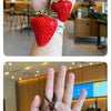 Un charm porte-clés de sac à main en fraise rouge vif, montrant la texture et la couleur vibrante du fruit.