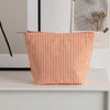 Pochette en crochet rayée orange et blanche posée sur une surface blanche.