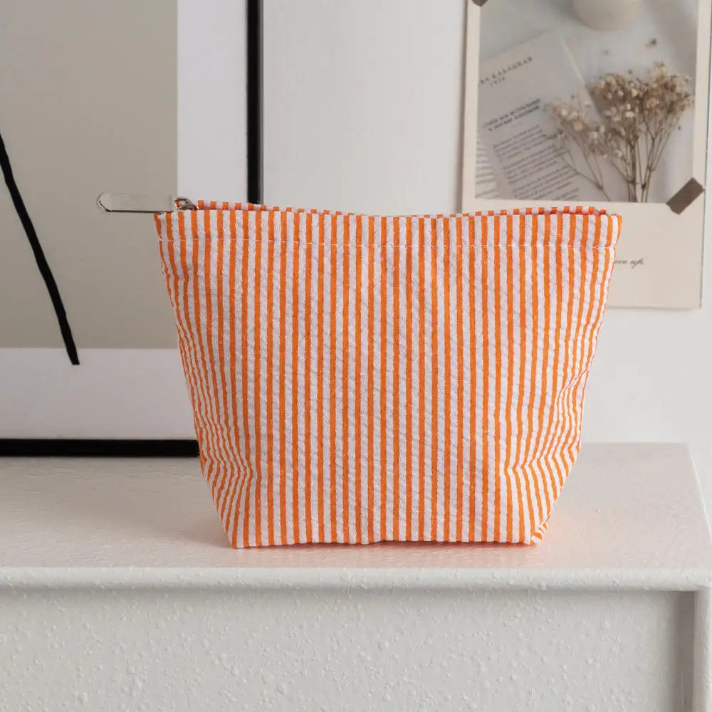 Pochette en crochet rayée orange et blanche posée sur une surface blanche.