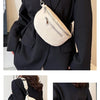 A woman wearing a black blazer holds a cream-colored PU leather multi-pocket crossbody bag with a silver chain.
