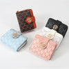 A collection of three compact wallets featuring different patterns and colors including brown plaid, black, and light blue.