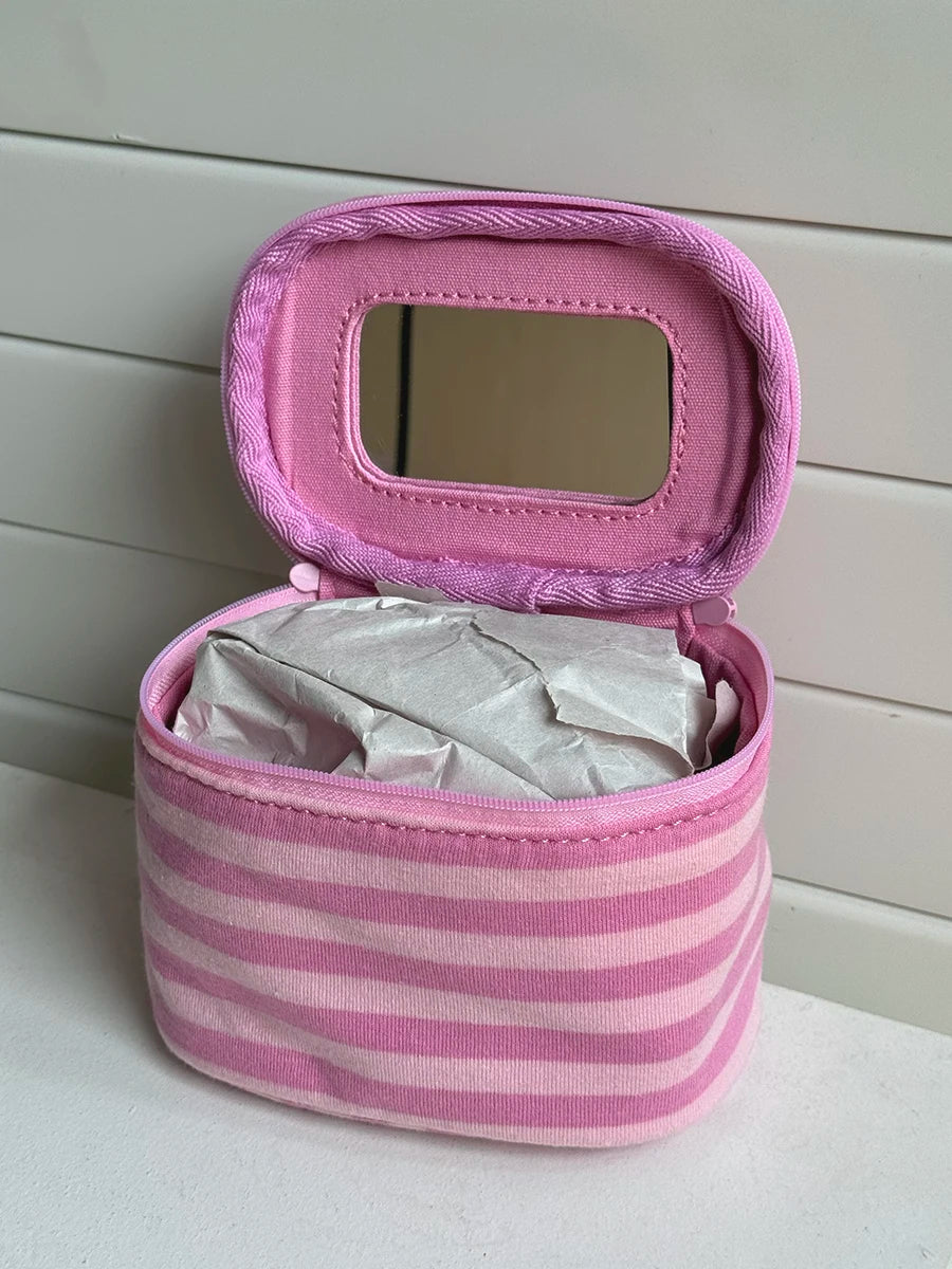A pink striped Y2K makeup bag with a mirror and zipper, made of cotton toiletry pouch material.