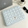 Light blue quilted laptop sleeve with a diamond pattern resting on a white surface.