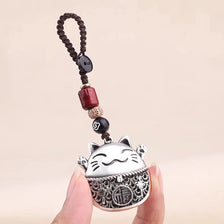 A silver cat key ring keychain with a black beaded chain is held by a hand.