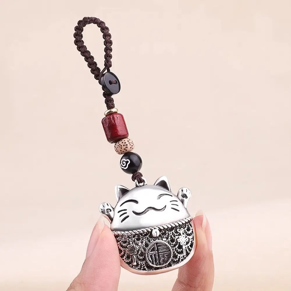 A silver cat key ring keychain with a black beaded chain is held by a hand.