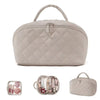 A light beige quilted makeup organizer bag with a handle, shown next to various makeup items.