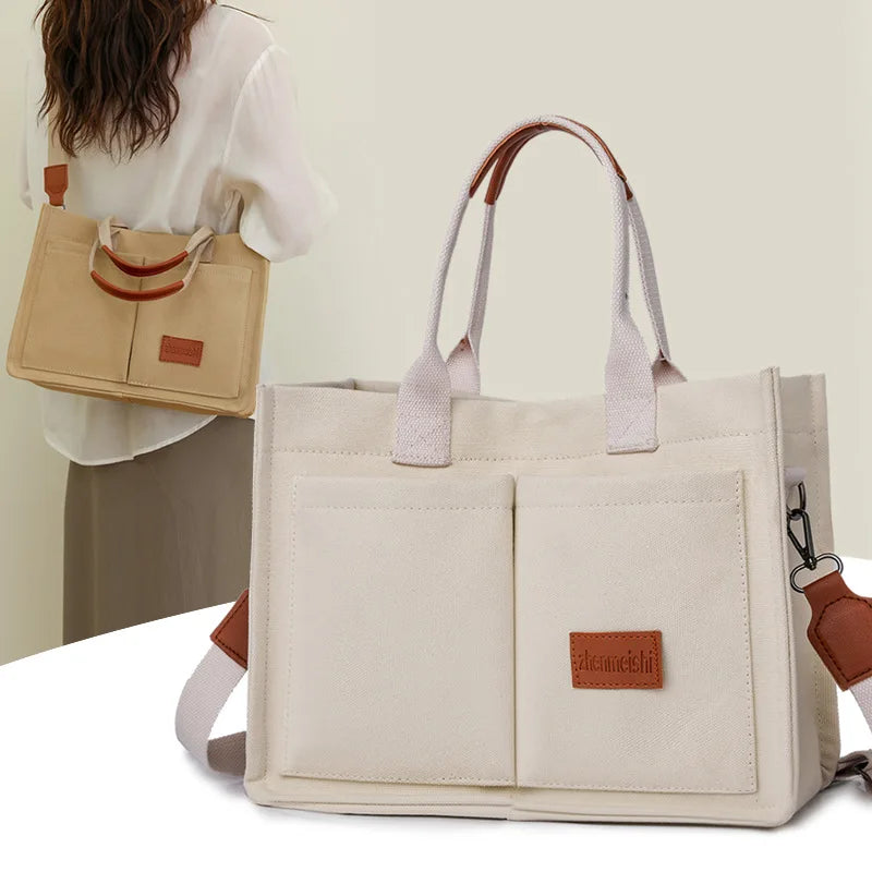 A beige canvas tote handbag with light pink leather accents is shown against a light background.