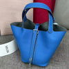 A bright blue leather bucket bag with a dark lining and silver hardware is shown on a gray surface.