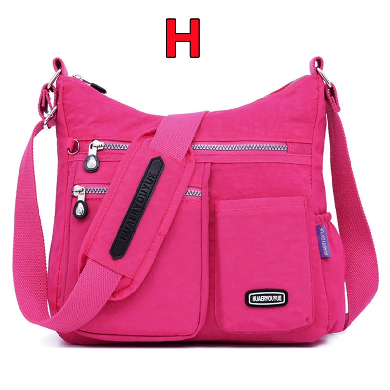 Helle pinke wasserdichte Nylon-Crossbodytasche mit schwarzem Riemen und Reißverschlusstaschen.