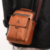 A brown vintage PU leather crossbody messenger bag with a dark brown strap worn by a person.