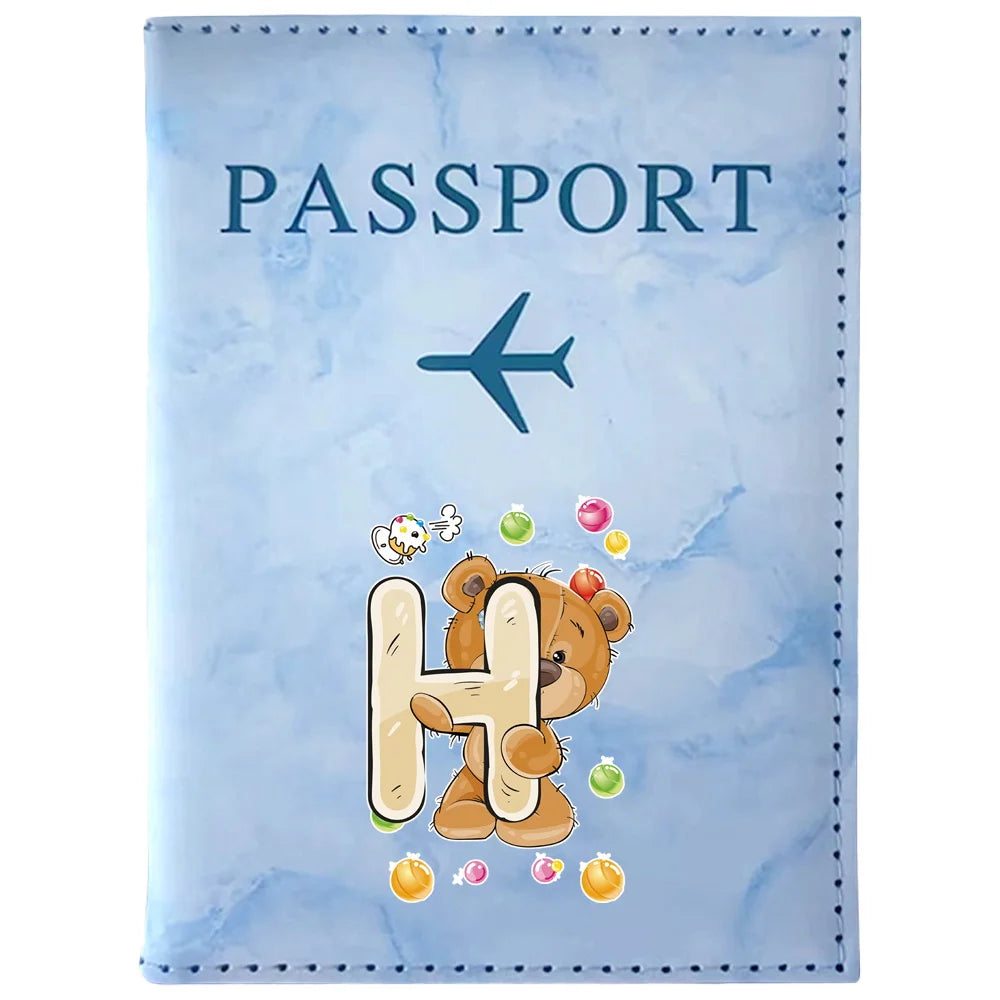 Light blue passport card holder featuring a vintage letter print of the letter H and small colorful elements.