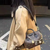 A person is wearing a tan leather coat and carrying a dark brown cowhide leather bag with a gold chain strap.