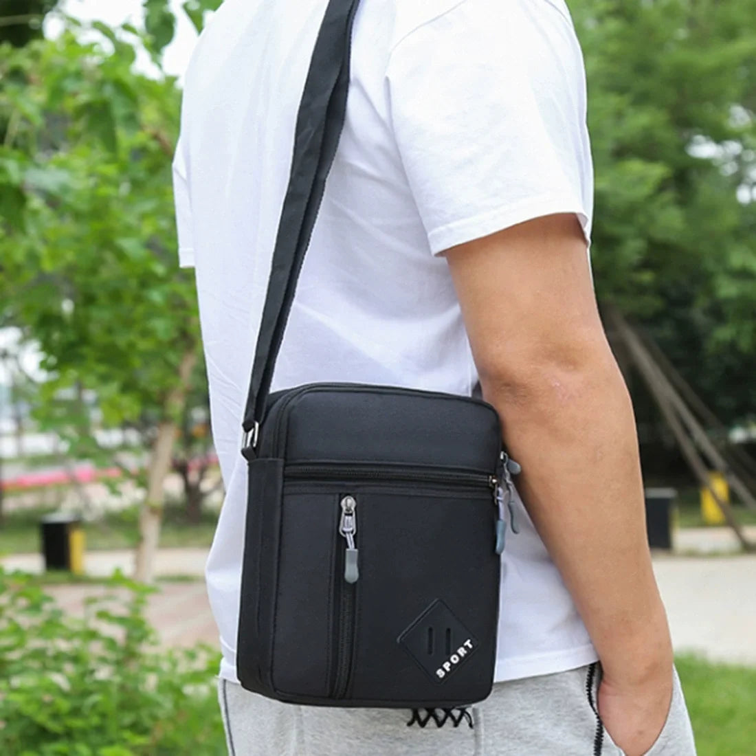 A man wearing a white t-shirt is holding a black lightweight crossbody sling bag.