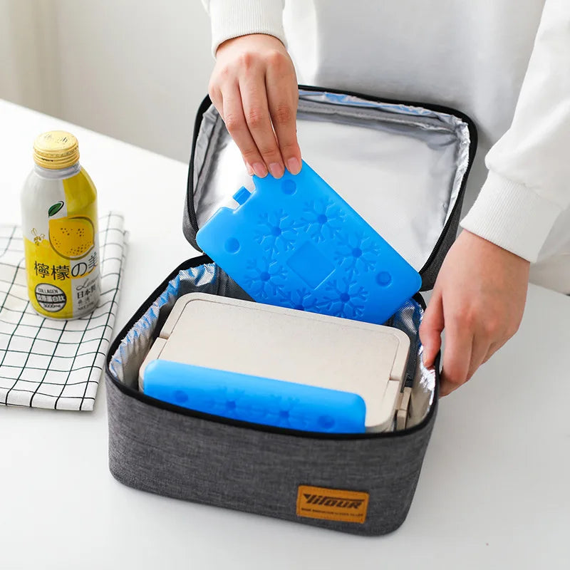 A hand is opening a gray reusable ice pack to reveal a blue silicone ice pack and a white case.