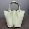 A light cream leather bucket bag with a vertical zipper closure and gold hardware.