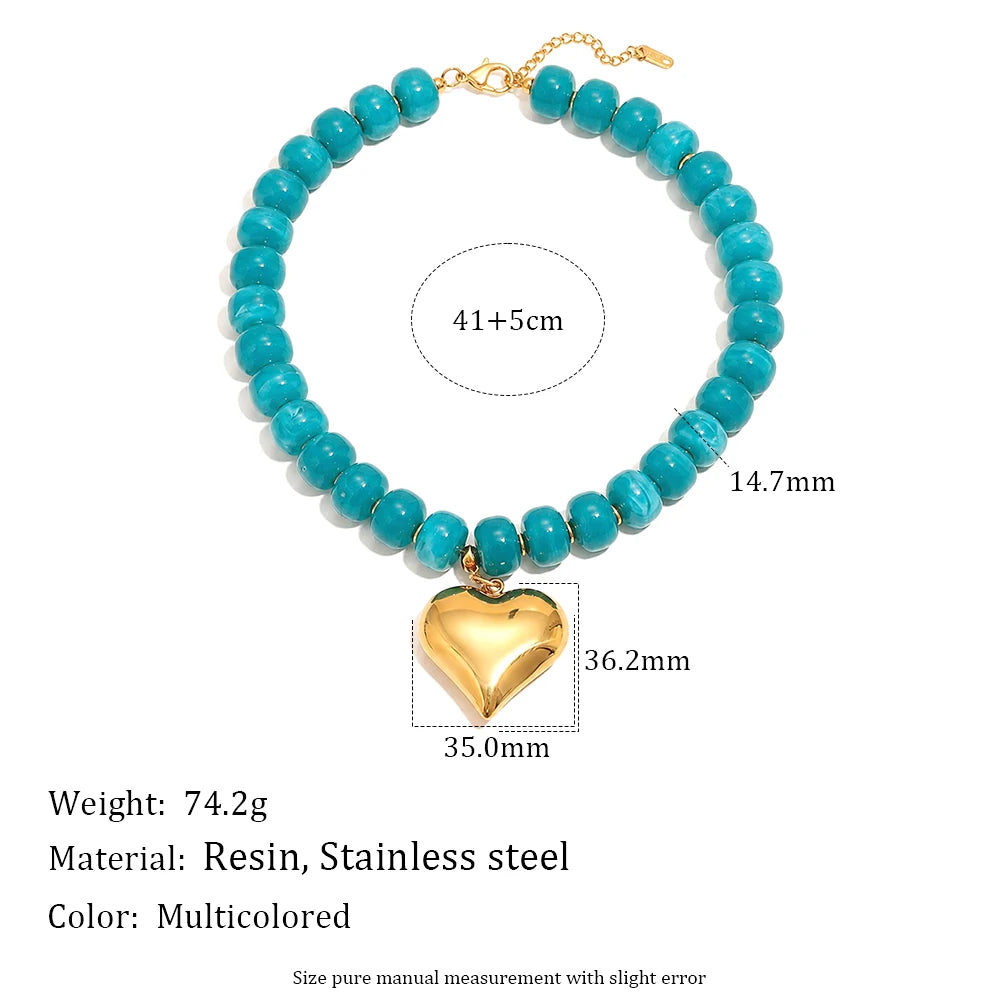 A necklace featuring light blue beads and a gold heart charm, made with resin and stainless steel.