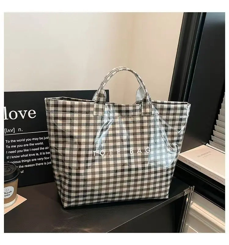 A transparent waterproof PVC tote bag with a black and white checkered pattern displayed on a dark surface.
