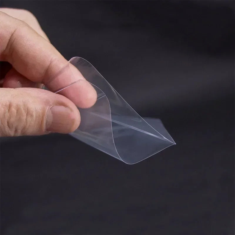 A hand holds a transparent plastic card sleeve protector, demonstrating the clear protective packaging.
